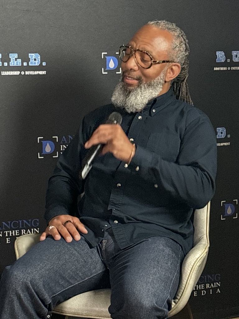 Heru TchaasAmen speaking with a microphone on the B.U.L.D. Podcast
