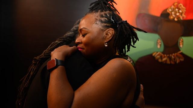 Heru TchaasAmen in a warm embrace with a community member