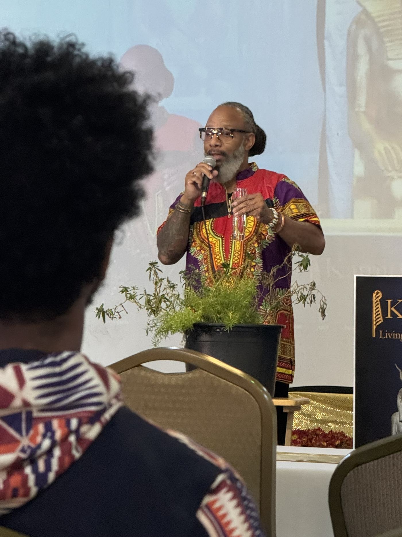 Heru TchaasAmen leading the KamitFest libation with Kamitic imagery projected behind him