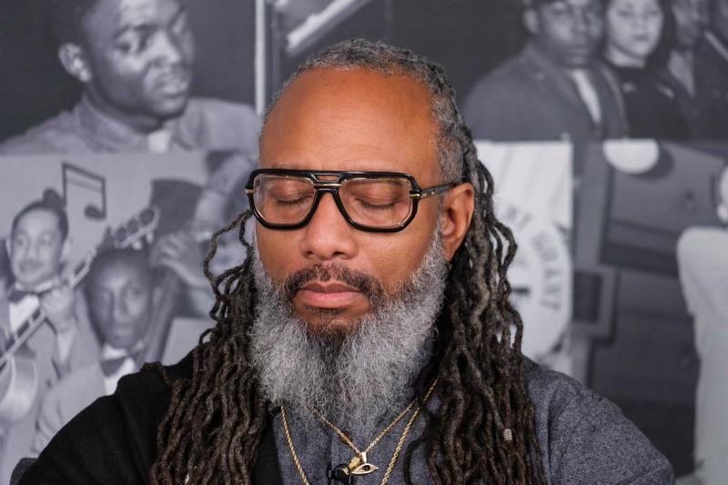Heru TchaasAmen in a moment of stillness, eyes closed, at Black Media Matters Studio, Converge Media